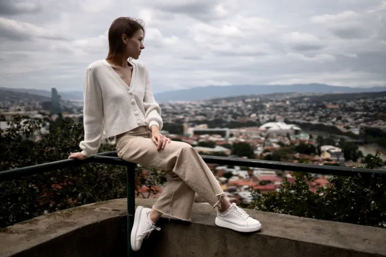 Que mettre avec un pantalon beige femme : mes meilleures associations J'ai longtemps laissé mon pantalon beige prendre la poussière dans le fond du placard. Pas par manque d'amour pour cette couleur, mais parce que je ne savais vraiment pas quoi mettre avec. Et bizarrement, c'est la pièce qui est devenue l'une des plus polyvalentes de ma garde-robe une fois que j'ai compris comment l'habiller. Blanc, noir, camel, imprimé léopard... le beige accepte presque tout. Je te donne ici toutes mes combinaisons préférées, celles que je porte vraiment au quotidien. Sommaire Pourquoi le pantalon beige est une base incontournable Avec du blanc : la valeur sûre Avec du noir : l'association qu'on n'ose pas assez Avec du camel et du marron : le monochrome chic Avec des couleurs vives : oser le contraste Avec des imprimés : le bon dosage Les chaussures qui changent tout Les erreurs à éviter FAQ Pourquoi le pantalon beige est une base incontournable Le beige, c'est une neutralité active. Ce n'est pas une couleur fade, c'est une couleur qui sert les autres. Le pantalon beige femme fonctionne un peu comme une page blanche : il accueille n'importe quelle idée sans jamais prendre le dessus. Ce que j'adore clairement dans cette pièce, c'est qu'elle traverse les saisons sans forcer. Style recherché Haut recommandé Chaussures Accessoires Casual décontracté T-shirt blanc oversize Baskets blanches Tote bag en toile Bureau chic Blazer camel + top crème Escarpins nude Sac structuré Soirée décontractée Top noir satiné Mules noires Clutch dorée Week-end nature Pull marron chunky Bottines camel Écharpe terracotta Look estival Crop top terracotta Sandales dorées Lunettes rondes Avec du blanc : la valeur sûre Le duo beige-blanc, pourquoi ça marche toujours J'ai dû mettre un haut blanc avec mon pantalon beige des dizaines de fois et je ne m'en lasse pas. C'est le genre d'association qui paraît banale jusqu'au moment où tu la vois sur toi. Il se passe quelque chose de lumineux, d'un peu intemporel. Le blanc crée un contraste doux avec le beige, sans jamais agresser le regard. Le secret, c'est vraiment la matière. Un t-shirt blanc basique en coton, c'est bien. Mais une chemise blanche légèrement oversize rentrée dans le pantalon, c'est mieux. Une blouse en soie ou en viscose, c'est encore un cran au-dessus. Le beige valorise vraiment les matières nobles, il leur donne une profondeur qu'elles n'auraient pas avec un jean bleu par exemple. Ce que je porte souvent : un top blanc à fines bretelles avec un blazer blanc cassé par-dessus, des mules beige ou nude, et un sac en paille l'été. Tu obtiens quelque chose de très clean, très parisien sans chercher midi à quatorze heures. Avec du noir : l'association qu'on n'ose pas assez Casser les codes avec le contraste beige-noir Pendant longtemps j'ai eu l'impression que le noir était trop fort pour le beige. Trop de contraste, trop de rupture. Et puis j'ai essayé et ça m'a clairement bluffée. Le noir apporte une structure au beige qui l'empêche de paraître mou ou sans personnalité. Un pull col roulé noir avec un pantalon beige tailleur, c'est chic et puissant. Tu peux aller au bureau ou à un dîner avec la même tenue sans changer quoi que ce soit. Ajoute des bottines noires à talon carré et un manteau en lainage noir, le look tient tout seul. Ce que j'ai remarqué, c'est que l'association marche encore mieux quand le pantalon beige est bien coupé, avec une belle tombée. Un beige froissé ou trop casual avec du noir ça fait moins bien. Le contraste appelle une certaine précision dans les pièces. Avec du camel et du marron : le monochrome chic L'art du total look dans les tons chauds C'est peut-être mon association préférée. Le beige avec du camel ou du marron, c'est un monochrome qui n'en a pas l'air. On ne perçoit pas forcément la coordination au premier coup d'oeil, mais on voit que quelque chose fonctionne très bien. C'est le genre de tenue dont on te demande "t'as trouvé ça où ?" sans que personne puisse vraiment dire ce qui rend l'ensemble aussi réussi. Un pull en maille camel avec un pantalon beige fluide et des bottines marron cognac Une veste en cuir camel portée sur un simple body beige Un manteau marron chocolat sur toute une tenue dans les tons neutres Ce que j'aime avec ces tons chauds, c'est qu'ils fonctionnent été comme hiver. L'été tu alléges avec des sandales camel et un top terracotta. L'hiver tu densifies avec des matières plus épaisses dans les mêmes tons. La palette reste cohérente, le confort aussi. Avec des couleurs vives : oser le contraste Le beige comme fond de tableau pour les couleurs fortes Le beige est le meilleur fond qui soit pour une couleur vive. Il ne lui vole pas la vedette, il la met en lumière. J'ai compris ça le jour où j'ai mis un pull vert sauge avec mon pantalon beige et que j'ai reçu trois compliments dans la même journée. Pas sur la couleur en particulier, mais sur l'ensemble. Les couleurs qui fonctionnent le mieux avec le beige : Le vert sauge ou kaki : naturel, terreux, dans la même famille de tons doux Le terracotta et le rouille : chaleureux, parfaits pour l'automne, très tendance depuis quelques saisons Le bleu cobalt ou électrique : un contraste plus affirmé mais magnifique, surtout avec un beige sable très clair Le bordeaux : élégant, parfait pour les soirées d'hiver Ce que j'évite personnellement : le jaune fluo ou le rose flashy. Pas que ce soit impossible, mais le rendu est souvent compliqué à équilibrer et ça demande un vrai savoir-faire stylistique que je n'ai pas forcément envie de déployer le matin à 7h30. Avec des imprimés : le bon dosage Imprimés et beige, une question d'équilibre Le pantalon beige accepte les imprimés mieux que la plupart des autres neutres. Parce qu'il ne rentre pas en compétition. Un pantalon noir avec un haut léopard, ça peut faire lourd. Un pantalon beige avec le même haut léopard, ça fait chic presque naturellement. J'ai longtemps pensé que les imprimés c'était pas pour moi, que je ne me sentais pas du coup capable de les intégrer sans faire trop. Et puis j'ai commencé par une petite touche : un foulard à motifs noué sur le sac, une paire de ballerines à motif léopard. Le pantalon beige absorbait l'imprimé sans que ça fasse criard. Ce que je recommande si tu débutes avec les imprimés : garder l'imprimé dans une seule pièce et habiller tout le reste en beige ou en une couleur neutre de la même palette. Le pantalon beige fait exactement ce travail de socle silencieux qui laisse l'imprimé respirer. Les chaussures qui changent tout Choisir ses chaussures selon l'effet voulu La chaussure transforme complètement la même tenue. Avec un pantalon beige et un haut blanc, tu vas dans trois directions totalement différentes selon ce que tu mets aux pieds. Des baskets blanches : look casual, léger, week-end. Des escarpins nude : look bureau, chic, allongé. Des bottines chunky noires : look rock, affirmé, plus urbain. Ce sont les trois paires que je sors le plus souvent avec mon pantalon beige et elles me permettent de ne jamais avoir l'impression de me répéter. Les sandales dorées méritent aussi une mention spéciale. Avec un pantalon beige fluide l'été, une paire de sandales plates ou à talon doré, c'est instantanément méditerranéen et chic. Ça ne demande aucun effort supplémentaire et le résultat est toujours là. Les erreurs à éviter Ce qui peut faire rater le look Il y a quelques pièges classiques avec le pantalon beige que j'ai tous faits avant de comprendre pourquoi ça ne fonctionnait pas. Le premier, c'est de négliger la coupe. Le beige est une couleur qui pardonne moins les coupes approximatives que le noir. Un pantalon trop large sans structure, trop court, ou avec une ceinture qui tombe mal, ça se voit immédiatement. Le beige mérite une coupe soignée. Le deuxième, c'est de confondre tous les beiges entre eux. Il y a le beige sable, le beige rosé, le beige grisé, le beige chaud. Selon la teinte exacte de ton pantalon, certains hauts vont mieux fonctionner que d'autres. Un beige très chaud avec un blanc froid ça peut légèrement jurer. Ça vaut le coup de tester à la lumière naturelle avant de sortir. Le troisième, c'est de tout neutraliser. Le pantalon beige n'a pas besoin qu'on l'entoure d'autres neutres absolus à tout prix. Une touche de couleur, un imprimé, un accessoire doré : c'est ce qui donne du caractère à la tenue. Sans ça, l'ensemble peut manquer de vie. FAQ Est-ce qu'on peut porter un pantalon beige en hiver ? Complètement. Le beige fonctionne très bien en hiver avec des matières plus épaisses : velours côtelé, laine, denim beige. Tu l'associes à des tons marron, camel ou à du noir et tu obtiendras un look parfaitement adapté à la saison froide. Quelle couleur de sac avec un pantalon beige ? Un sac en cuir cognac, camel ou marron est une valeur sûre. Le noir fonctionne aussi très bien. Si tu veux ajouter une touche de fantaisie, un sac coloré dans les tons terracotta, vert kaki ou bordeaux peut faire toute la différence. Le pantalon beige est-il adapté au bureau ? Oui, c'est même une excellente pièce pour le bureau. Associé à un blazer structuré, une blouse ou un pull fin, il donne une allure professionnelle sans être austère. La clé, c'est la coupe : un pantalon tailleur ou droit bien ajusté ira mieux qu'un modèle trop décontracté. Comment éviter l'effet "trop sage" avec un pantalon beige ? Joue sur les textures, les matières et les volumes. Un haut en cuir, une veste oversize, des chaussures à détails originaux... C'est la façon la plus simple de donner du caractère à une tenue autour du beige sans perdre son côté élégant. Le beige convient-il à toutes les carnations ? Le beige existe dans plein de nuances, donc oui. Les carnations claires iront souvent mieux avec un beige rosé ou cendré, les carnations dorées ou foncées seront sublimées par un beige chaud, sable ou caramel. L'important est de tester la teinte exacte du pantalon proche du visage pour voir l'effet produit.